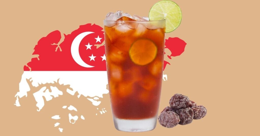 A wide 16:9 lifestyle food recipe photo showcasing a tall glass of iced Singaporean Teh O Limau Peng lime tea next to Calamansi Sour Plum