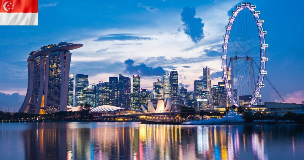 A wide 16:9 scenic city view of the modern Singapore skyline at dusk, showcasing the glowing Singapore Flyer wheel and the Marina Bay Sands harbor view reflecting over the water.
