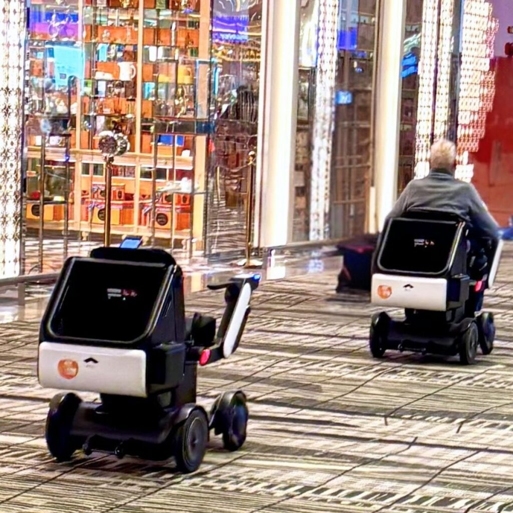 An innovative, autonomous robotic wheelchair navigating a flat, modern terminal walkway at Singapore Changi Airport.