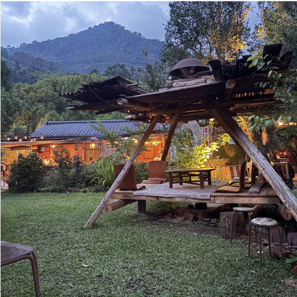 A cozy, warmly lit house nestled in the mountains during a peaceful dusk.