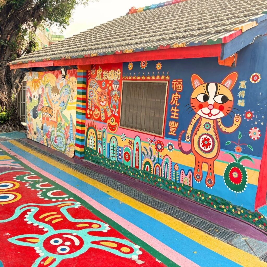 Colorful artwork and a vibrant tiger drawing on a building at Rainbow Village in Taichung.