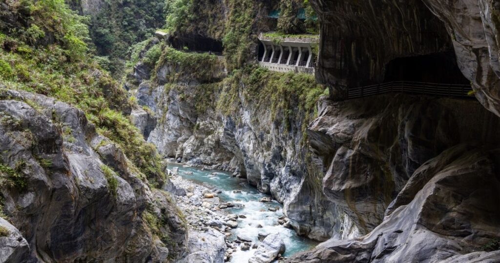 Scenic view of the dramatic Hualien Taroko Gorge in Taiwan, showing narrow roads carved directly into the massive, steep mountain rock faces.