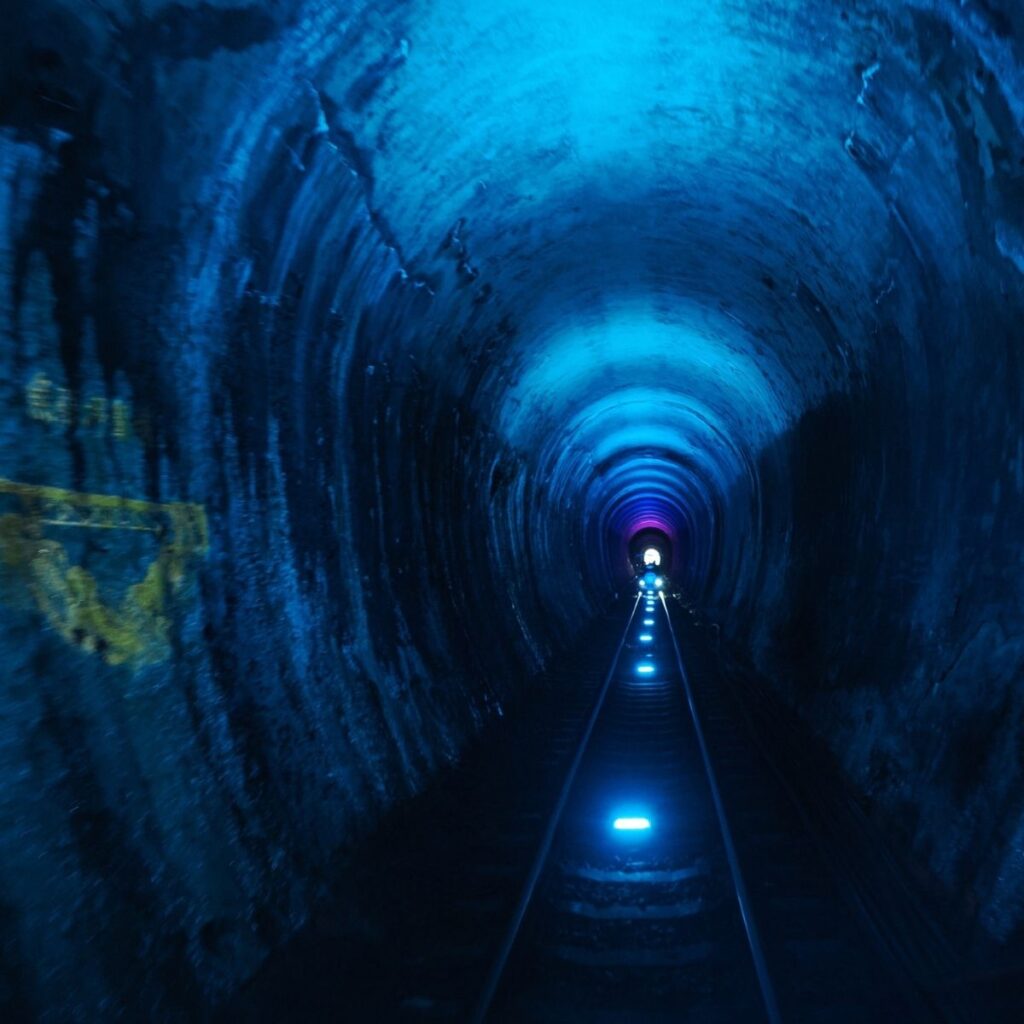 An old train tunnel in Sanyi illuminated from within by a striking blue light.