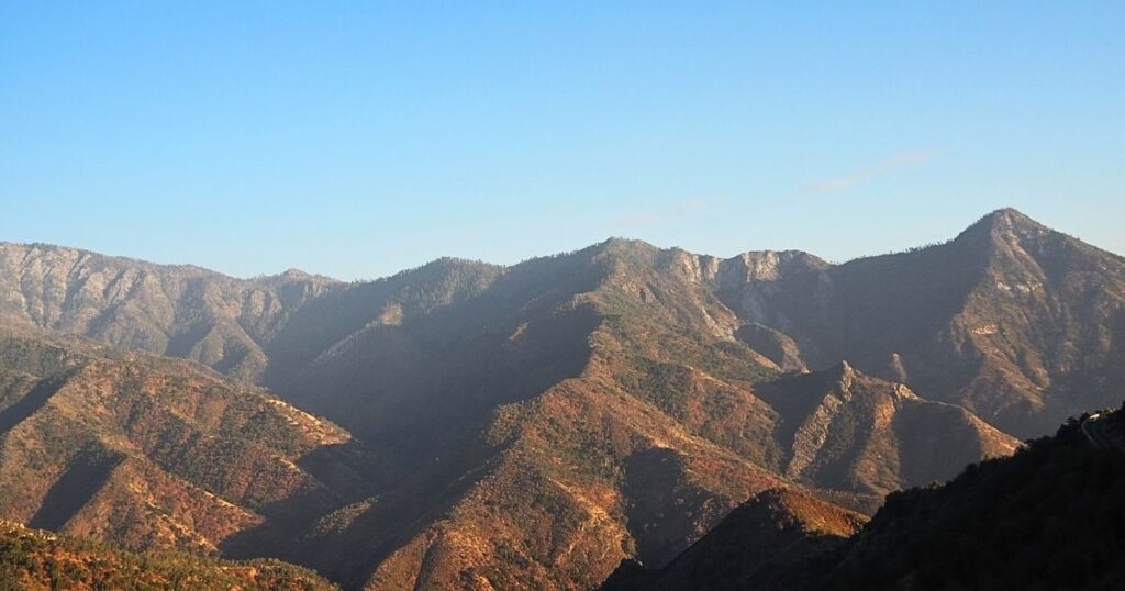 Kings Canyon National Park scenic drive view of massive bare stone mountains and deep valleys under a clear blue sky.